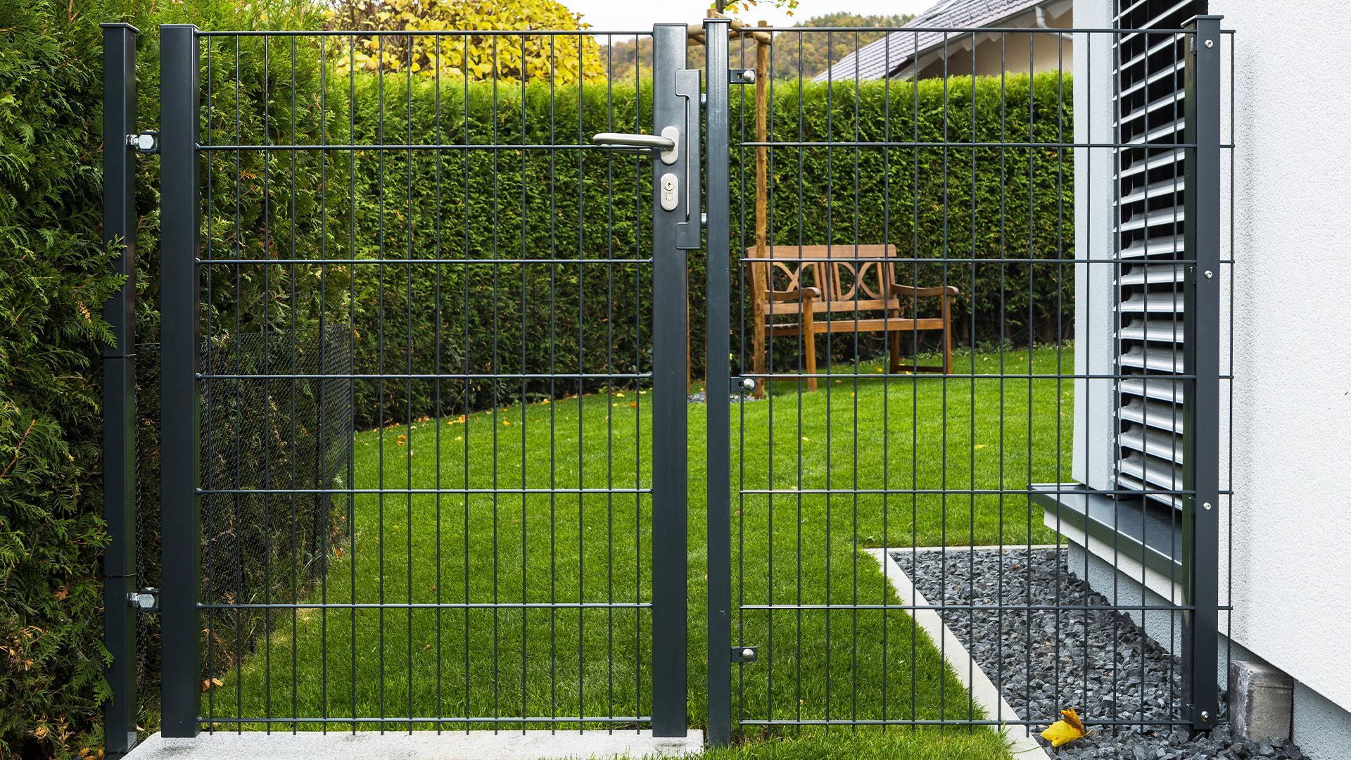 Eine Universalpforte an einem Haus mit Hecke im Hintergrund.